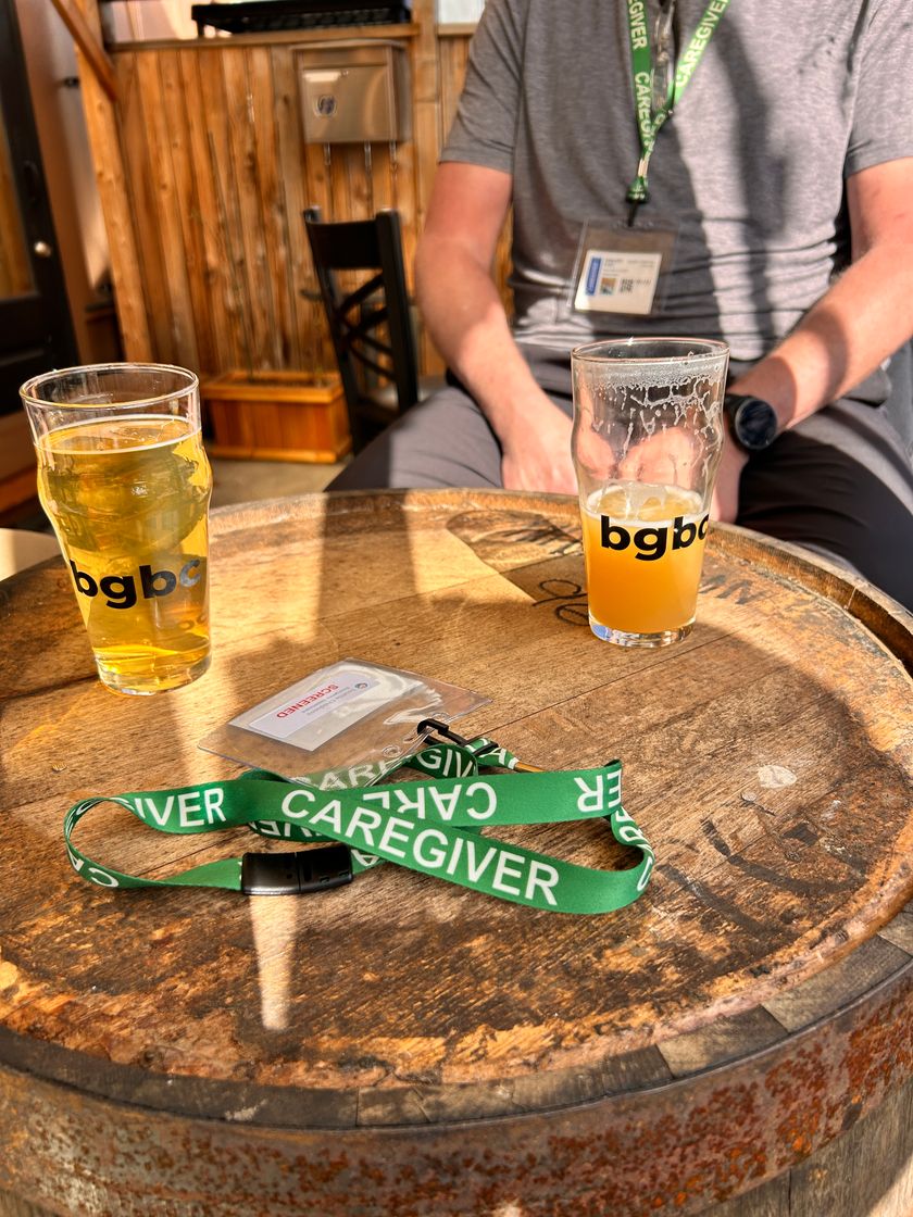 A Seattle Children's caregiver badge and lanyard on a barrel table next to two BGBC pint glasses